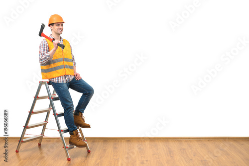 The happy man with the ax standing on the ladder on the white wall background
