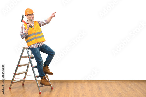 The happy man with the ax on the ladder gesturing on the white wall background