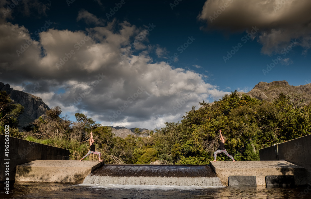 female performing yoga pose with scenic mountain and river background