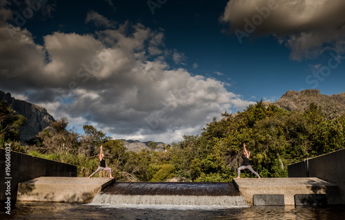 female performing yoga pose with scenic mountain and river background