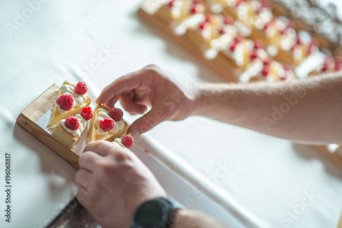 pieces of cheesecake with hands, confectioner hands at work