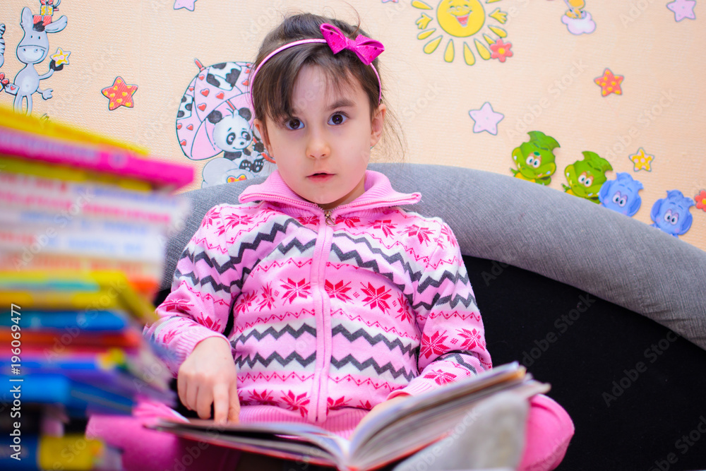 Cute girl on the background of her toys with a book Cute girl on the background of her toys with a book