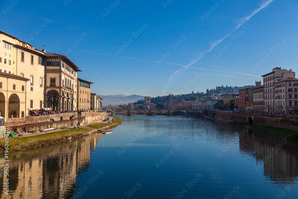 Cityscape view on Arno river from Ponte Vecchio bridge in Florence. Reflections on water. Old colorful houses on the side. Tuscany, Italy