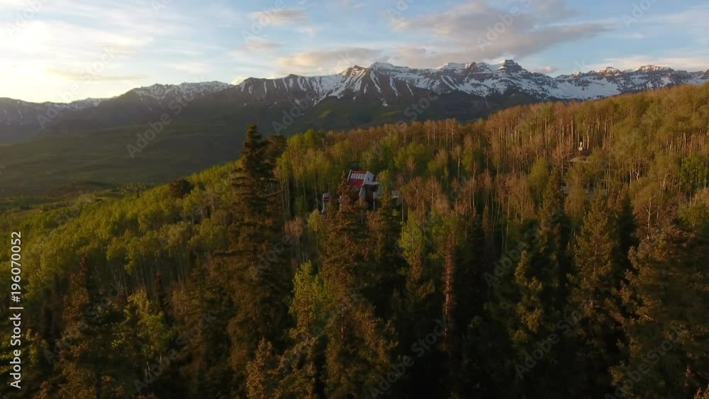 Through Treetops Towards House and Stunning Mountain Range at Sunset Through Treetops Towards House and Stunning Mountain Range at Sunset