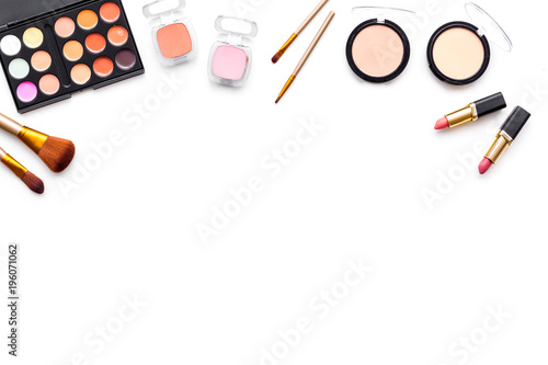 Makeup background. Eyeshadow palette, rouge, powder, brushes, lipstick on white background top view copy space