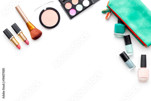 Makeup pattern. Eyeshadow, rouge, powder, brushes, lipstick, nail polish in cosmetic bag on white background top view copy space