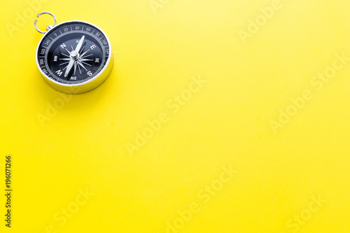 Compass on yellow background top view copy space