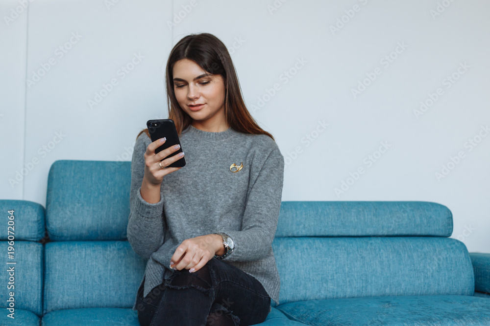 Obraz premium girl with smartphone on the sofa
