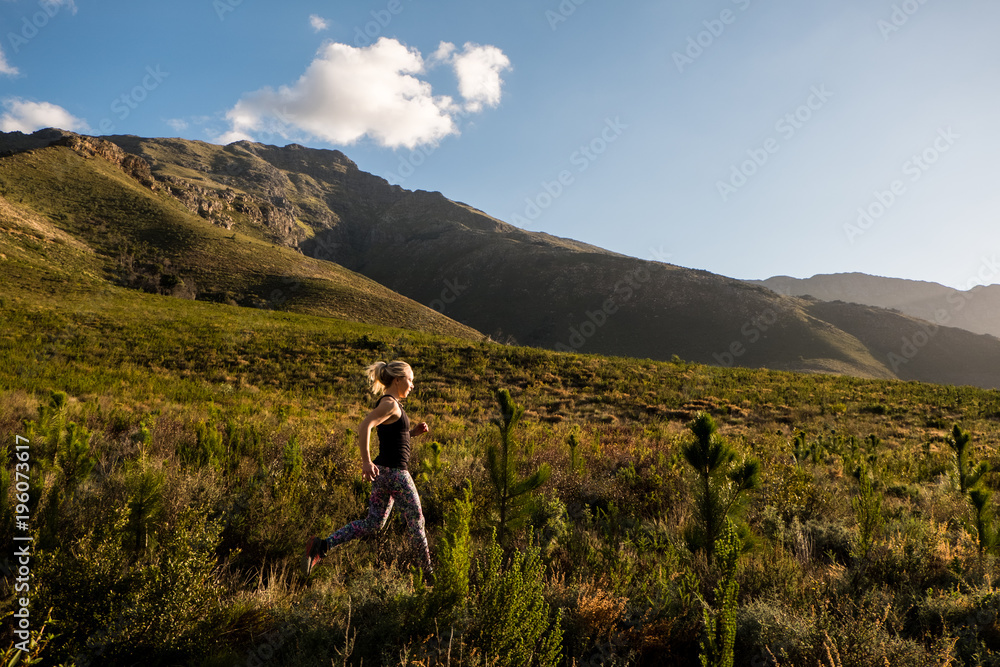 female trail runner in the mountains with beautiful light