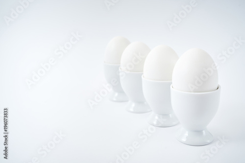 Obraz na plátně White eggs standing on egg cup isolated on white background, copy space