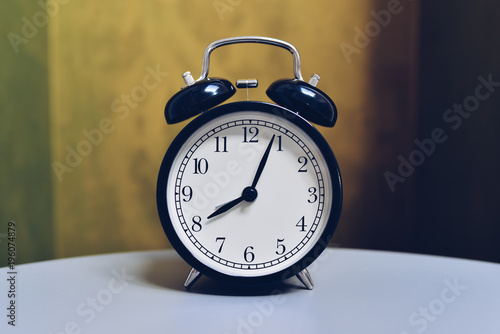 Retro alarm clock on table with vintage color background