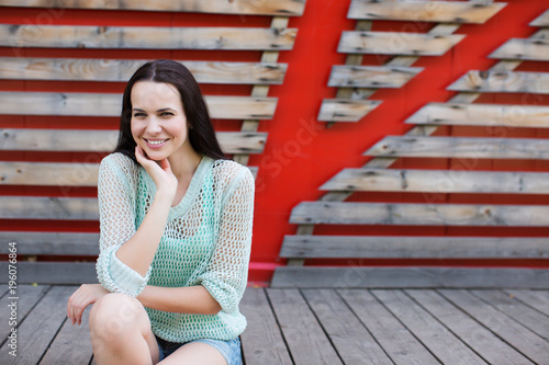 Portrait of a beautiful woman in denim shorts sitting on a wooden background.