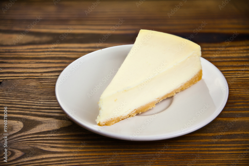 classic cheesecake on white plate on wooden table classic cheesecake on white plate on wooden table