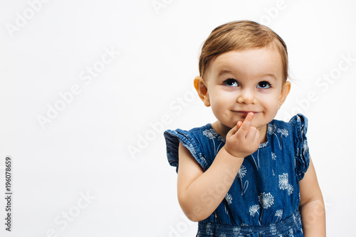 Make a wish - Small child with finger on mouth looking up, isolated on white background