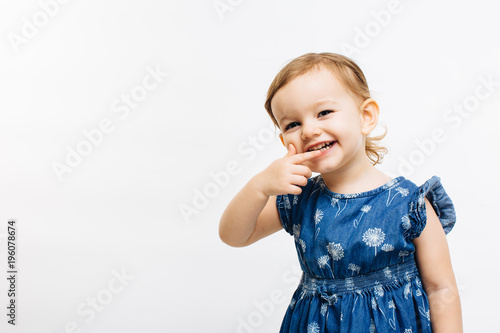 Fun portrait of a little girl with a big smile and hand on chin, isolated on white