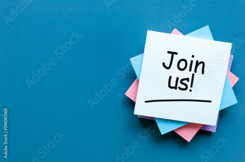 Join us sign on wooden cubes on pile of papers for notes at blue background photo
