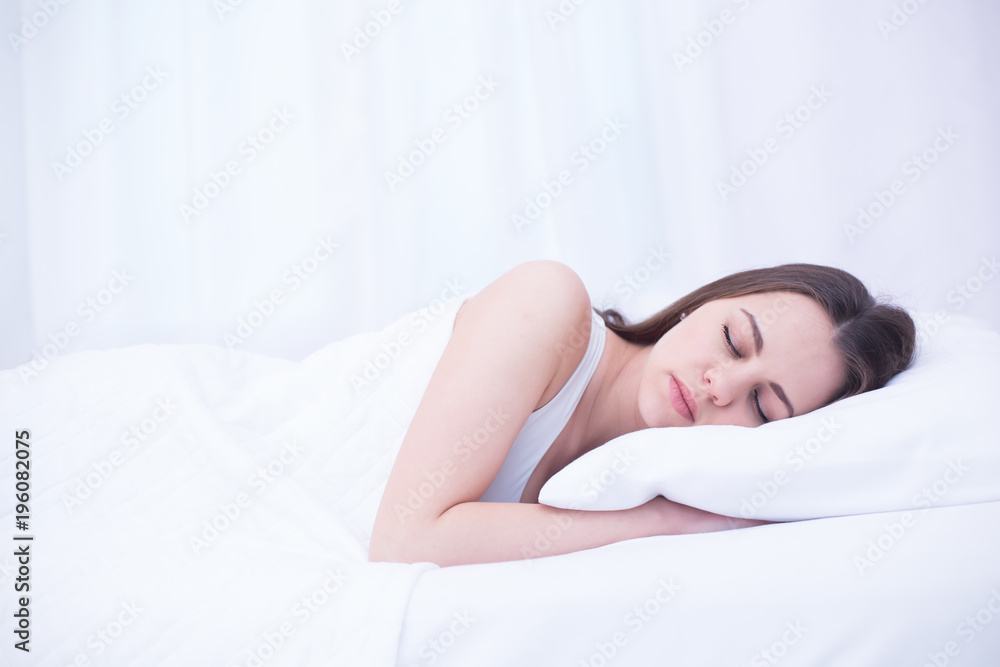 Young beautiful smiling woman is sleeping sweetly in a white bed at home. Relax and rest. Young beautiful smiling woman is sleeping sweetly in a white bed at home. Relax and rest.