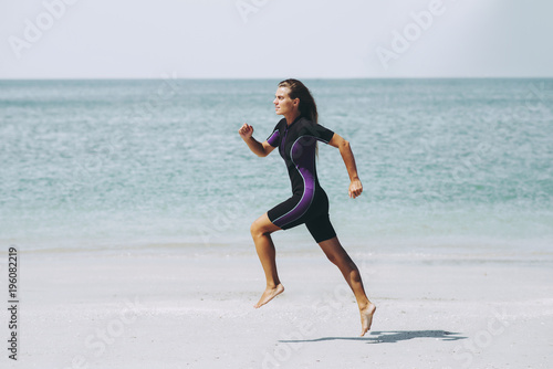 Beautiful woman in wetsuit on the idyllic beach