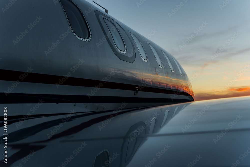 Last rays of sunlight reflect on on the fuselage an d Wing of a business jet. 