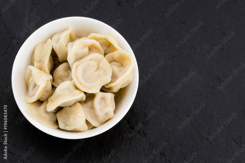 Traditional russian pelmeni, ravioli, dumplings with meat on black stone background . Copyspace Traditional russian pelmeni, ravioli, dumplings with meat on black stone background . Copyspace