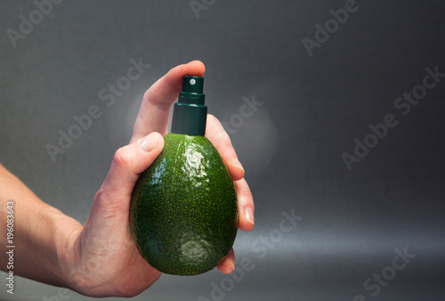 hand holding avocado with cream dispenser - natural cosmetics concept