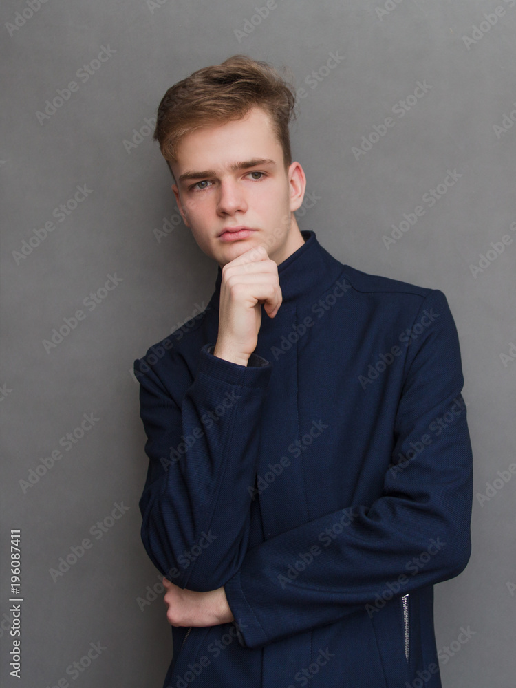 portrait of an attractive stylish serious young man, teenager in a coat and glasses