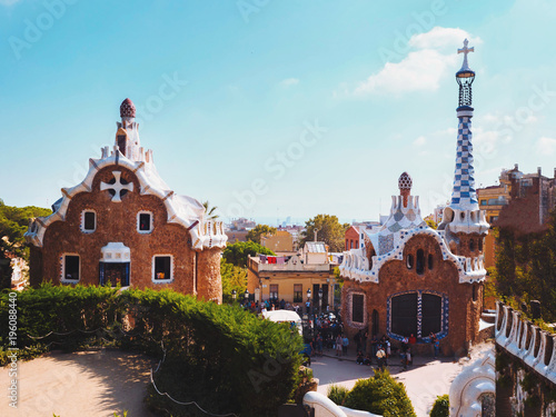 Barcelona, Catalonia, Spain: the Park Guell of Antoni Gaudi at sunset. The two buildings at the entrance of the park and Gaudi's mosaic work on the main terrace.