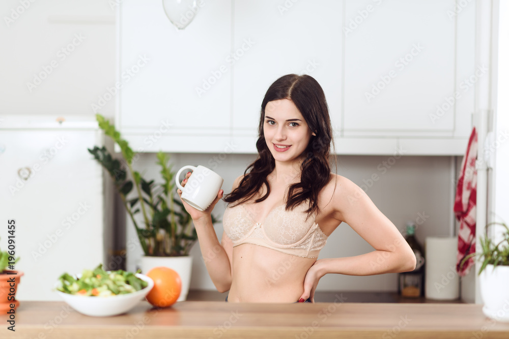 Young woman in underwear enjoying coffee or tea in the kitchen Young woman in underwear enjoying coffee or tea in the kitchen