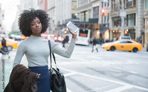 Woman with mobile device waiting for rideshare car service photo