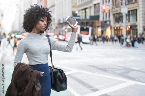 Woman with mobile device waiting for rideshare car service photo