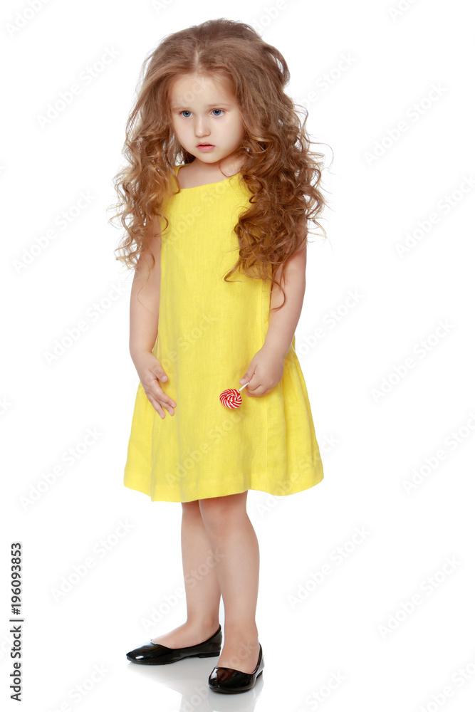 A little girl licks a candy on a stick. A little girl licks a candy on a stick.