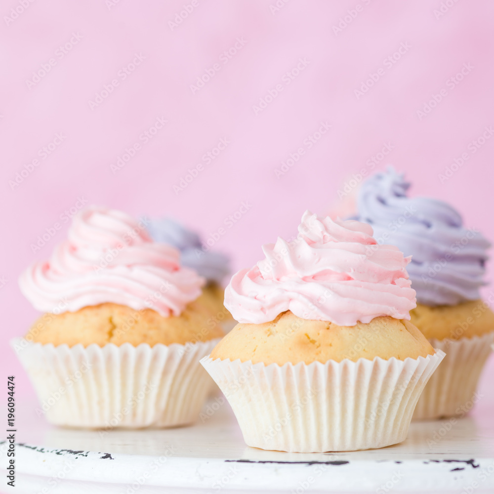Cupcakes decorated with pink violet buttercream on shabby shic stand on pink pastel background.
