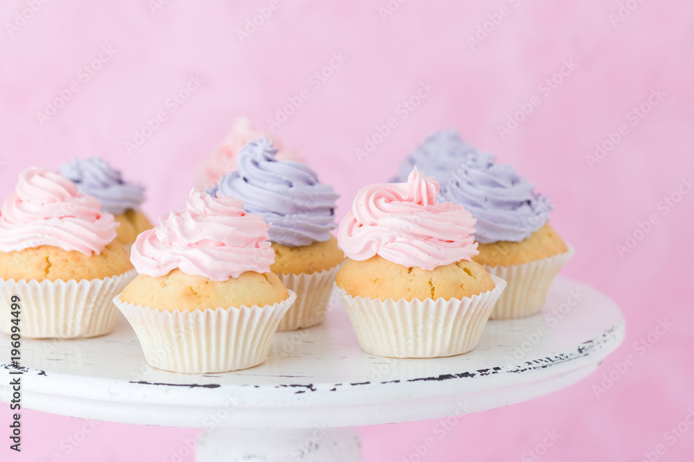 Cupcakes with violet and pink buttercream on shabby shic stand on pink pastel background.