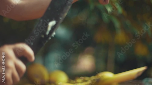 Young male tourist chops the top of a coconut with a machete to open it up and then hands it to another person