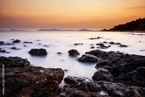 long exposure shooting of small island boat and rock in smoky and soft sea water with blue sky, Sky burst, blurred motion