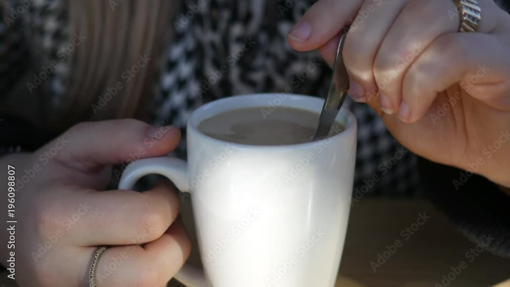 Close up of woman stirring an Irish coffee beverage in a mug on trendy diner in cafe Close up of woman stirring an Irish coffee beverage in a mug on trendy diner in cafe