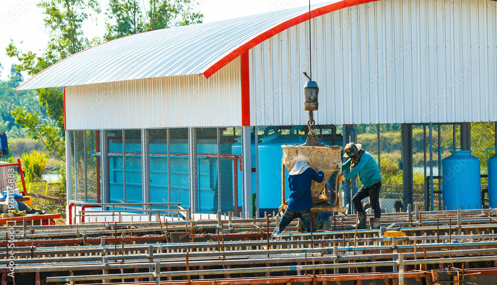 Naklejka premium Group of construction workers pouring wet concrete using concrete bucket into the timber form work at the construction site.