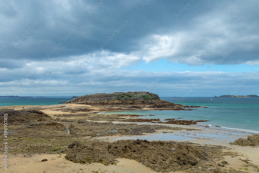 French beach with small island, rocks, stones and cloudy cold windy day