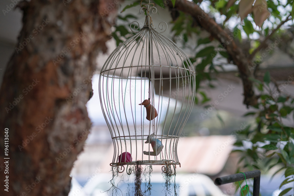 Bird statue in a bird cage in the garden.