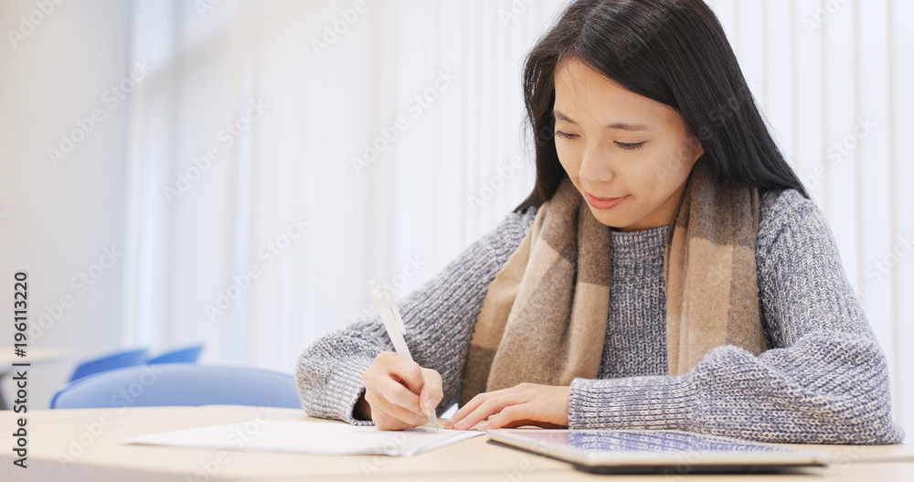 Student writing on note and doing revision in library Student writing on note and doing revision in library