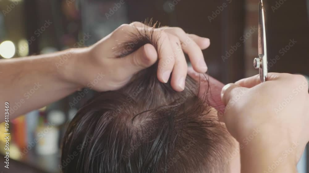 Close-up of barber cuts the hair by scissors at barbershop in slow motion. Close-up of barber cuts the hair by scissors at barbershop in slow motion.