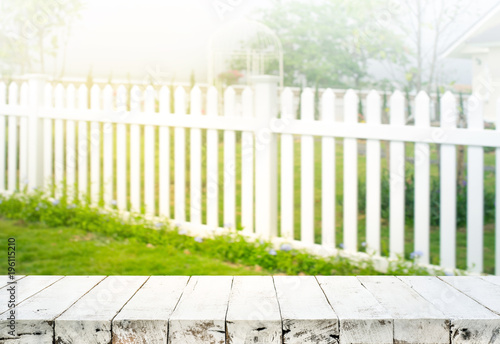 Wood table top on blur of white fence and garden background