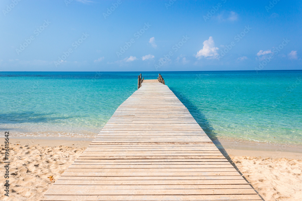 Obraz premium Drewniany most na tropikalnej plaży i błękitne niebo
