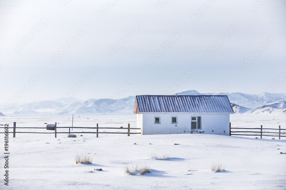 small white house in a snow covered valley in the middle of mountains of Northern Mongolia