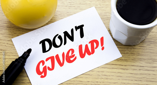 Conceptual hand writing text showing Don t Give Up. Business concept for Motivation Determination, written sticky note empty paper, Wooden background with copy space, Coffee and marker photo