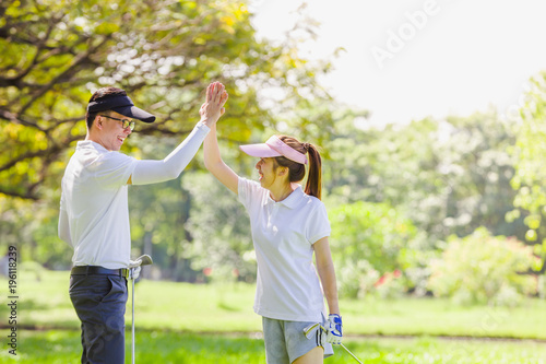 Golfer enjoying giving high-five at golf the game on field and shaking hands.