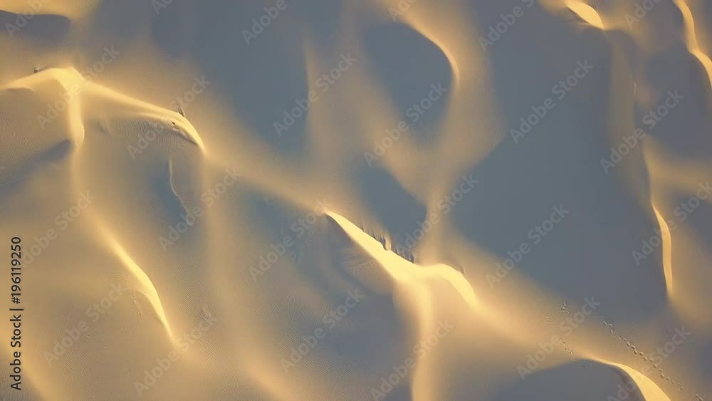 Flying forward above the sand dune with shadow and light pattern.