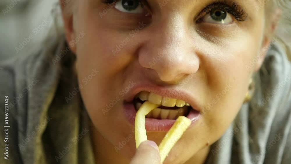 close-up woman eating junk food with great enjoyment. girl eats french fries. slow motion close-up woman eating junk food with great enjoyment. girl eats french fries. slow motion