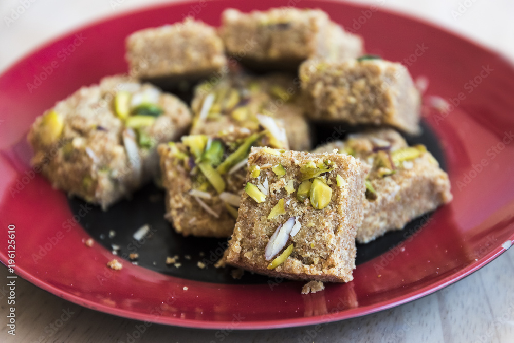 Mohanthal (sweetened gram flour fudges made with Ghee, and flavored with saffron and almonds) a Traditional Gujarati Sweet in Rajkot, Gujarat, India Mohanthal (sweetened gram flour fudges made with Ghee, and flavored with saffron and almonds) a Traditional Gujarati Sweet in Rajkot, Gujarat, India