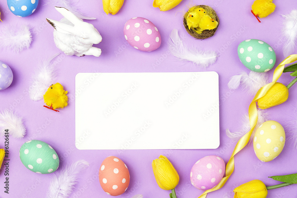 Blank paper card with colored eggs, feathers and tulip on violet background. Space for text. Blank paper card with colored eggs, feathers and tulip on violet background. Space for text.